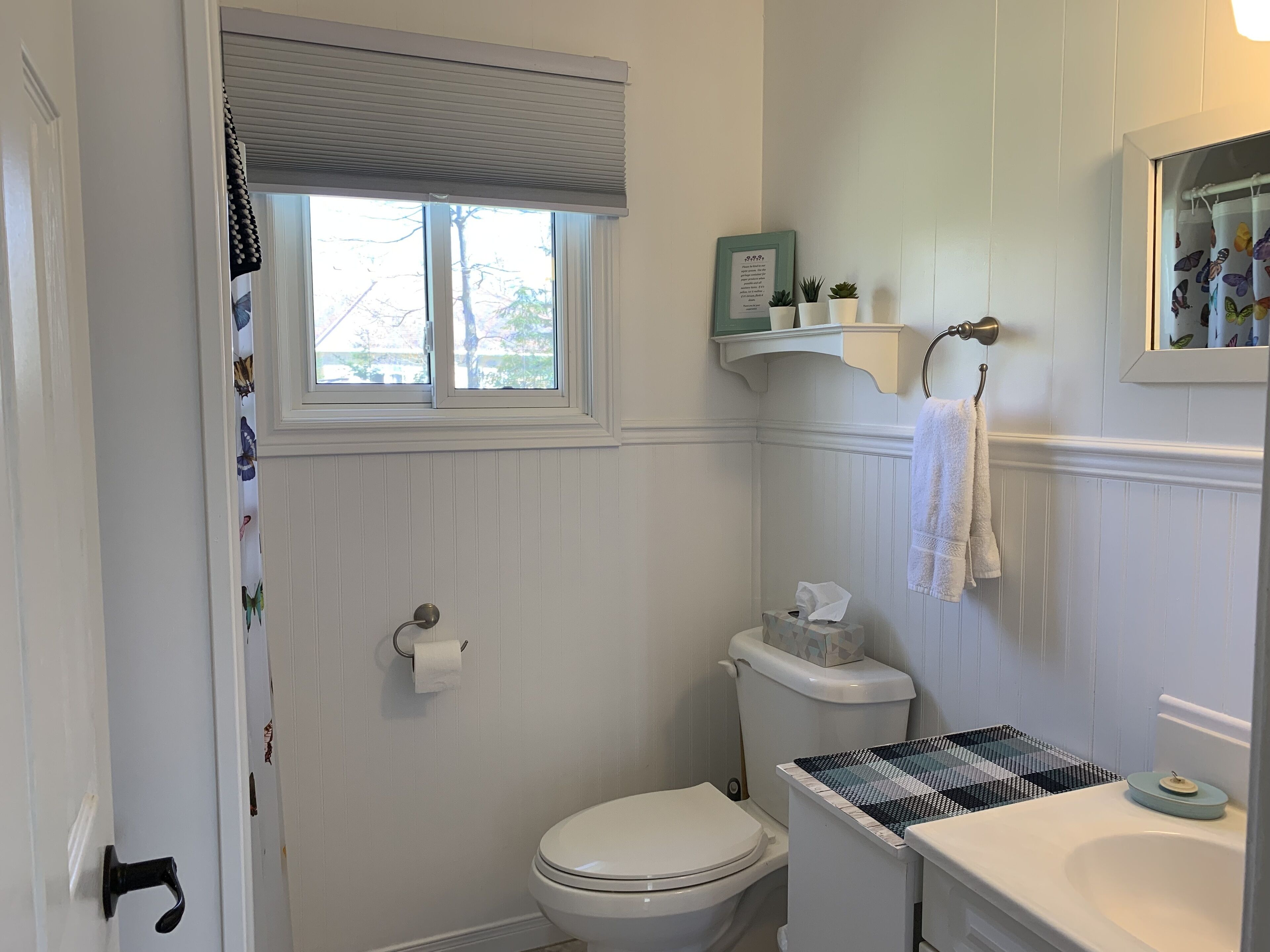 A bathroom with a toilet, sink, and window.