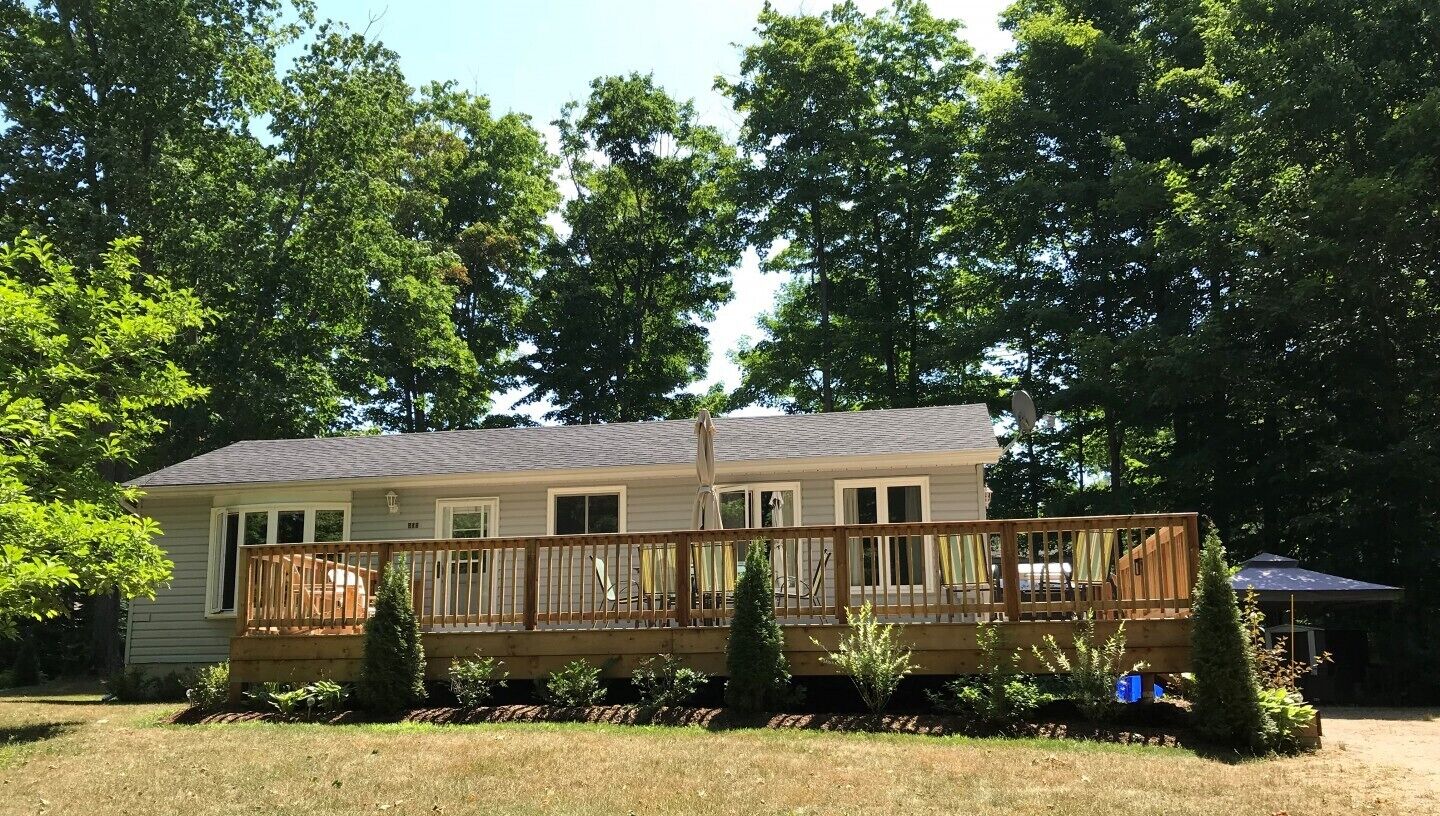 A two-story house with a wooden deck and a covered patio area.