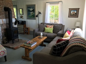 A cozy living room with a fireplace, a sofa, a coffee table, and a bookshelf. - Traditional cottage in historic trinity (Trinity, Trinity Bay)