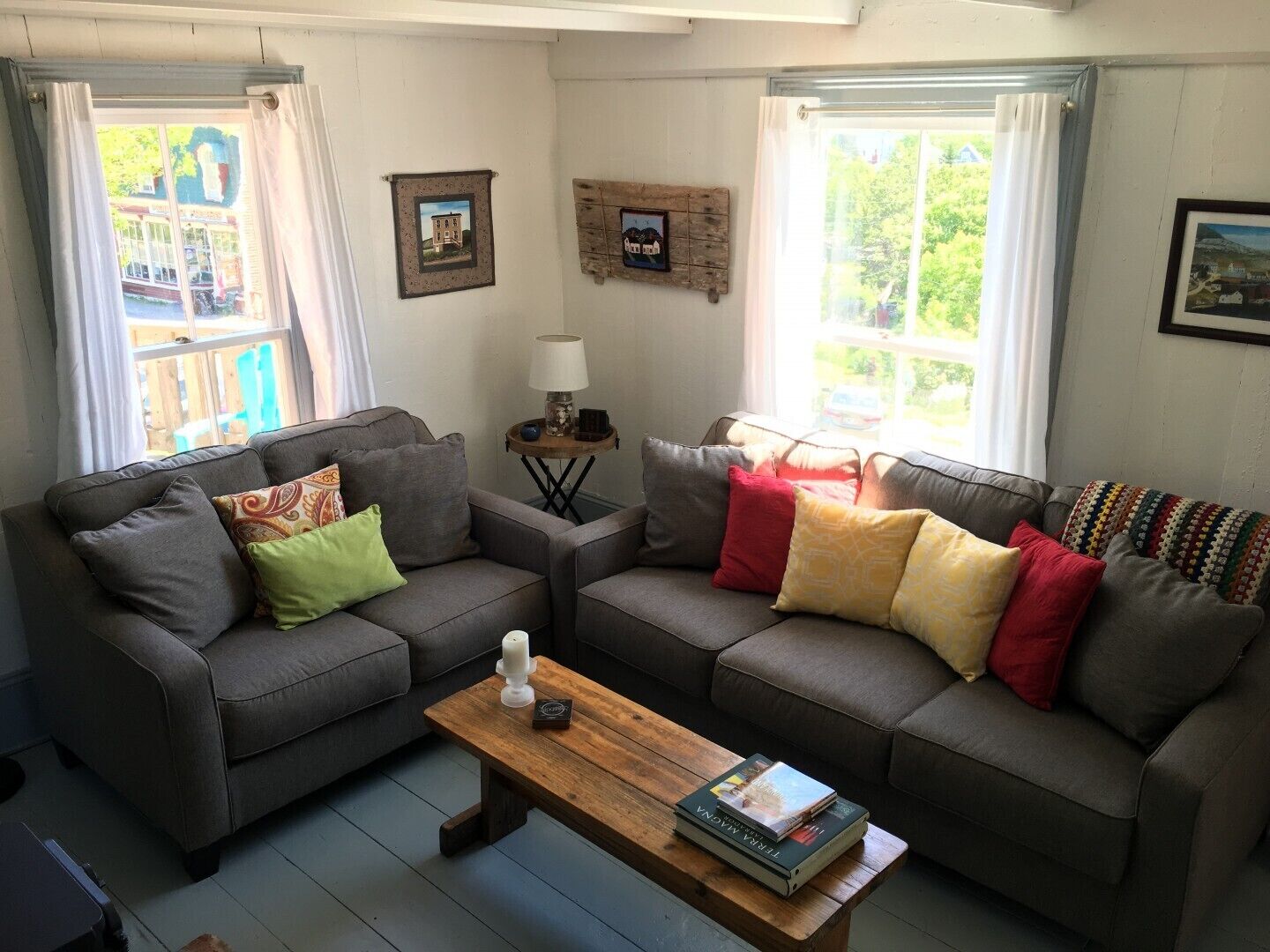 A cozy living room with two grey sofas, a wooden coffee table, and a small side table with a lamp.