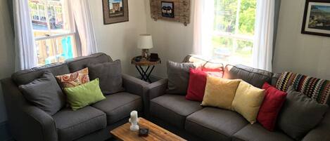 A cozy living room with two grey sofas, a wooden coffee table, and a small side table with a lamp.