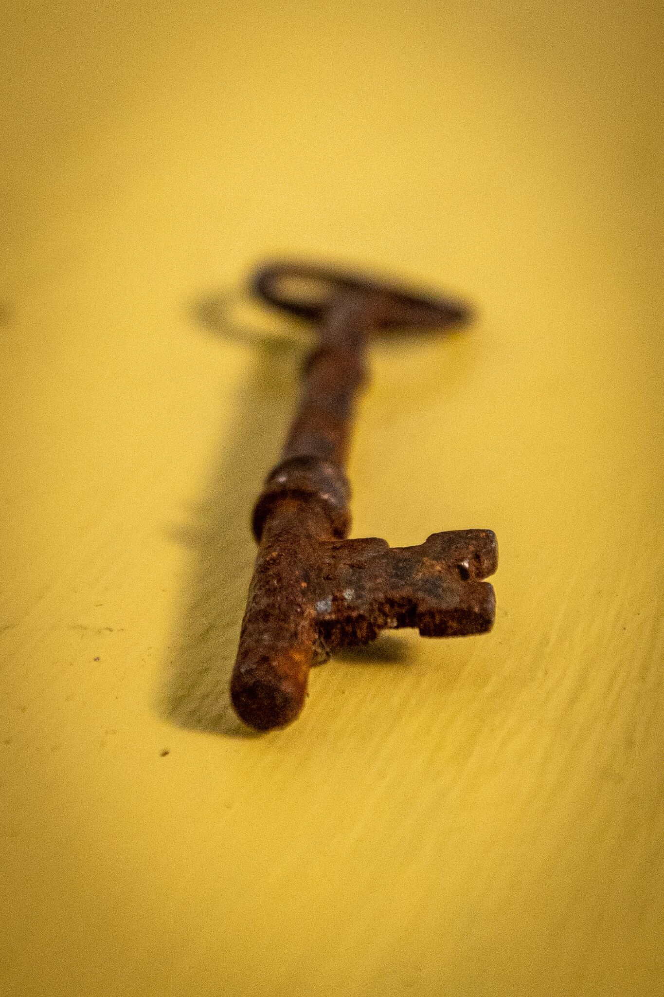 A rusty key on a yellow surface.