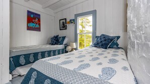 Une chambre avec deux lits, une fenêtre et une affiche accrochée au mur.