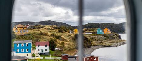 A coastal village with colorful houses, a beach, and a view of the sea through a window.