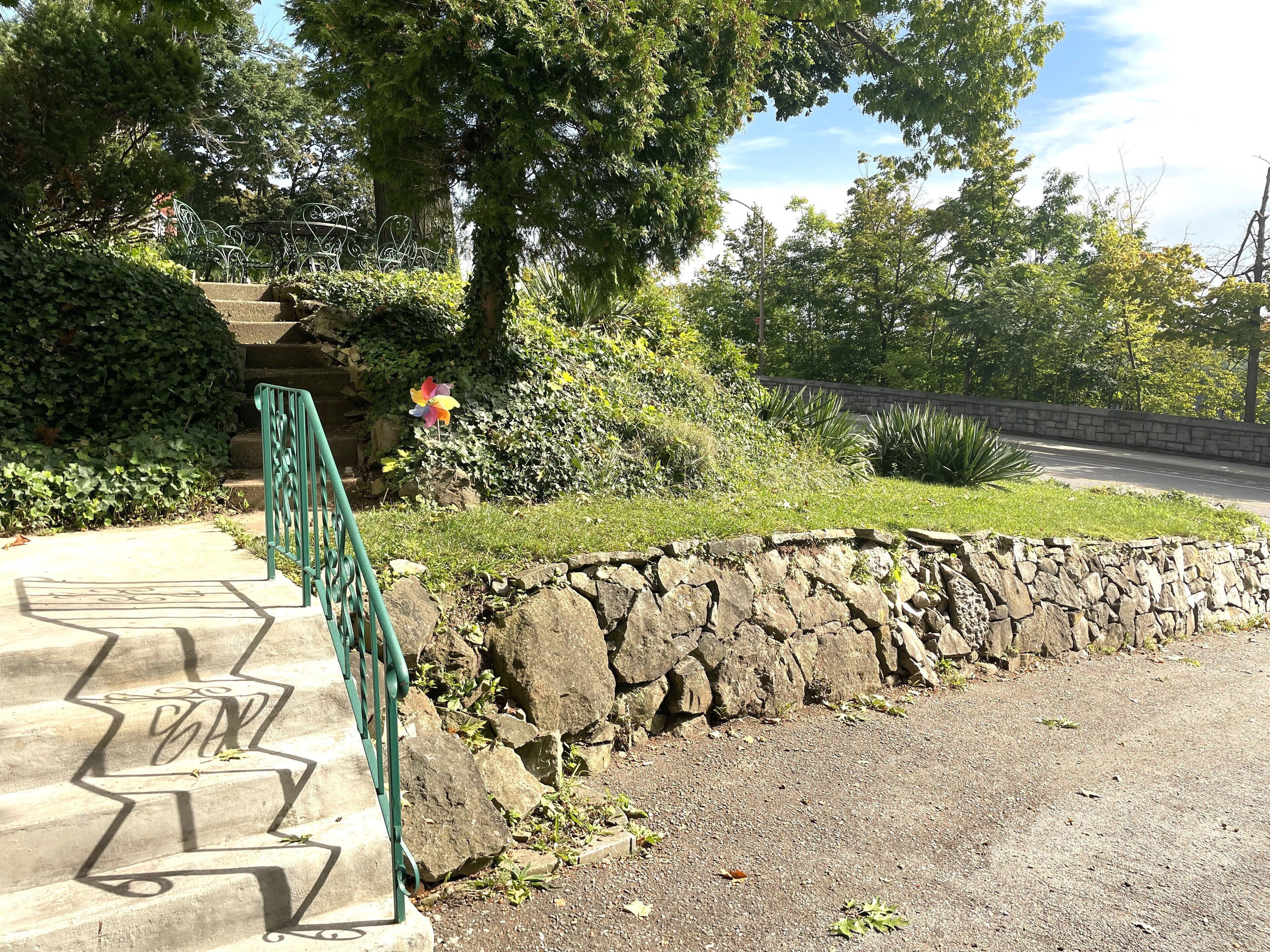 A stone retaining wall with steps leading up to a metal gate.