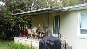 A single-story house with a covered porch, a dining table and chairs, and a covered object on the porch. - Simcoe Georgina Family Cottage Winter-Summer Rent 1hr from Toronto (Willow Beach)