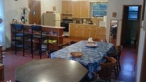 A compact kitchen with wooden cabinets, a dining table with chairs, and a clock on the wall. - Simcoe Georgina Family Cottage Winter-Summer Rent 1hr from Toronto (Willow Beach)