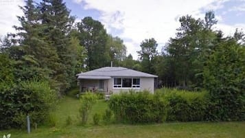 Situated in a lush environment, this house offers a tranquil retreat with a front porch perfect for outdoor dining or relaxation.