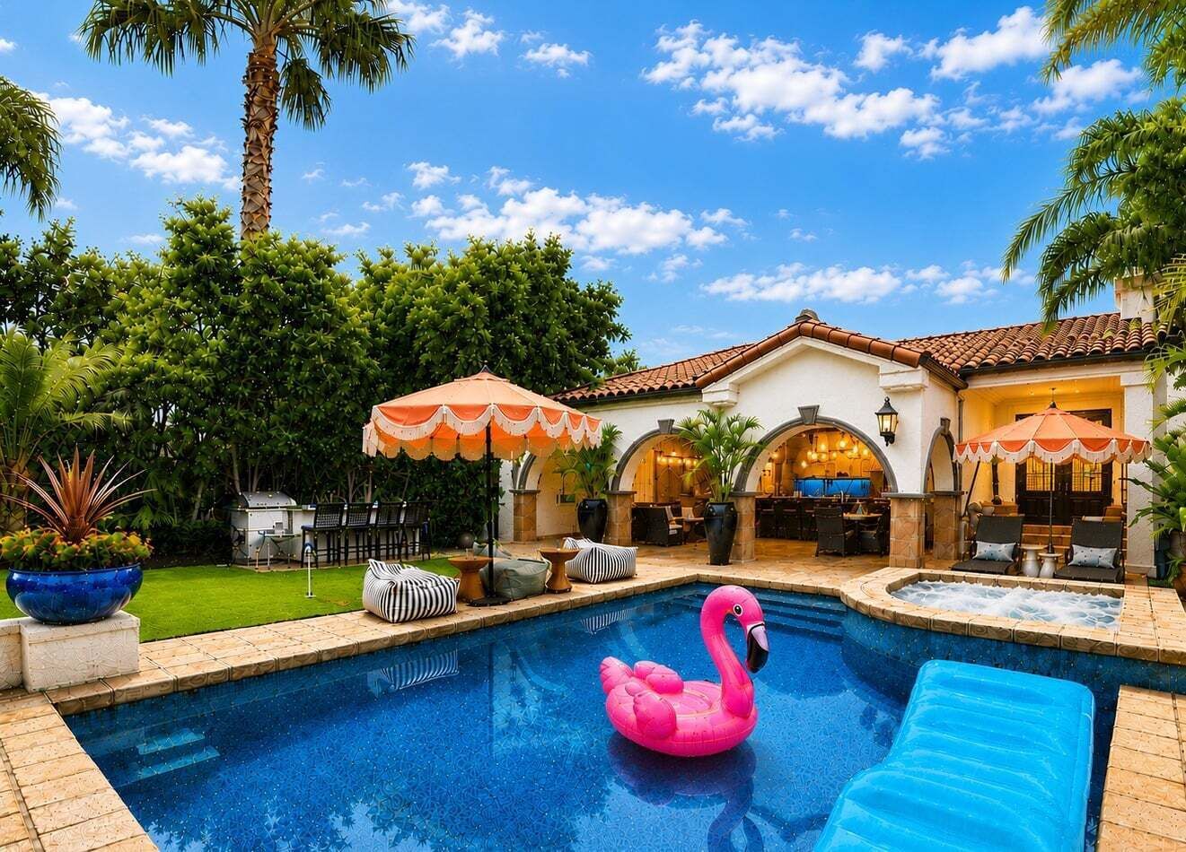 En pool med en rosa uppblåsbar flamingofigur, omgiven av utomhusmöbler och parasoller.