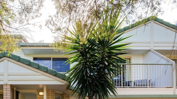 Une maison à deux étages avec un garage, une véranda et un petit jardin.