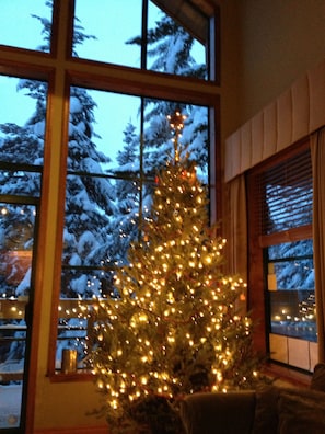 Enjoy a serene winter wonderland view from the large window, with a festive Christmas tree adding to the cozy ambiance.