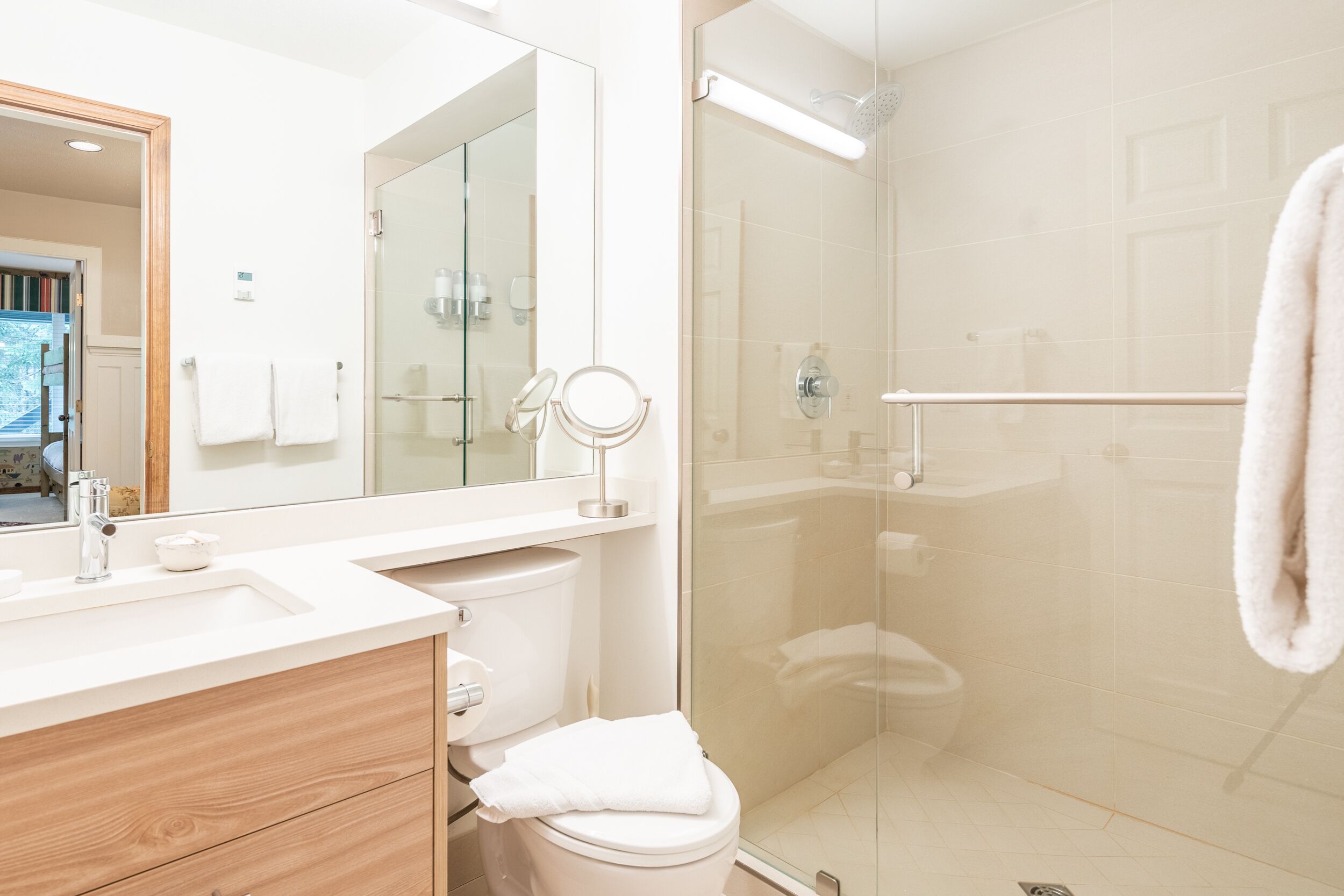A modern bathroom with a glass shower enclosure, a white sink, and a mirror.