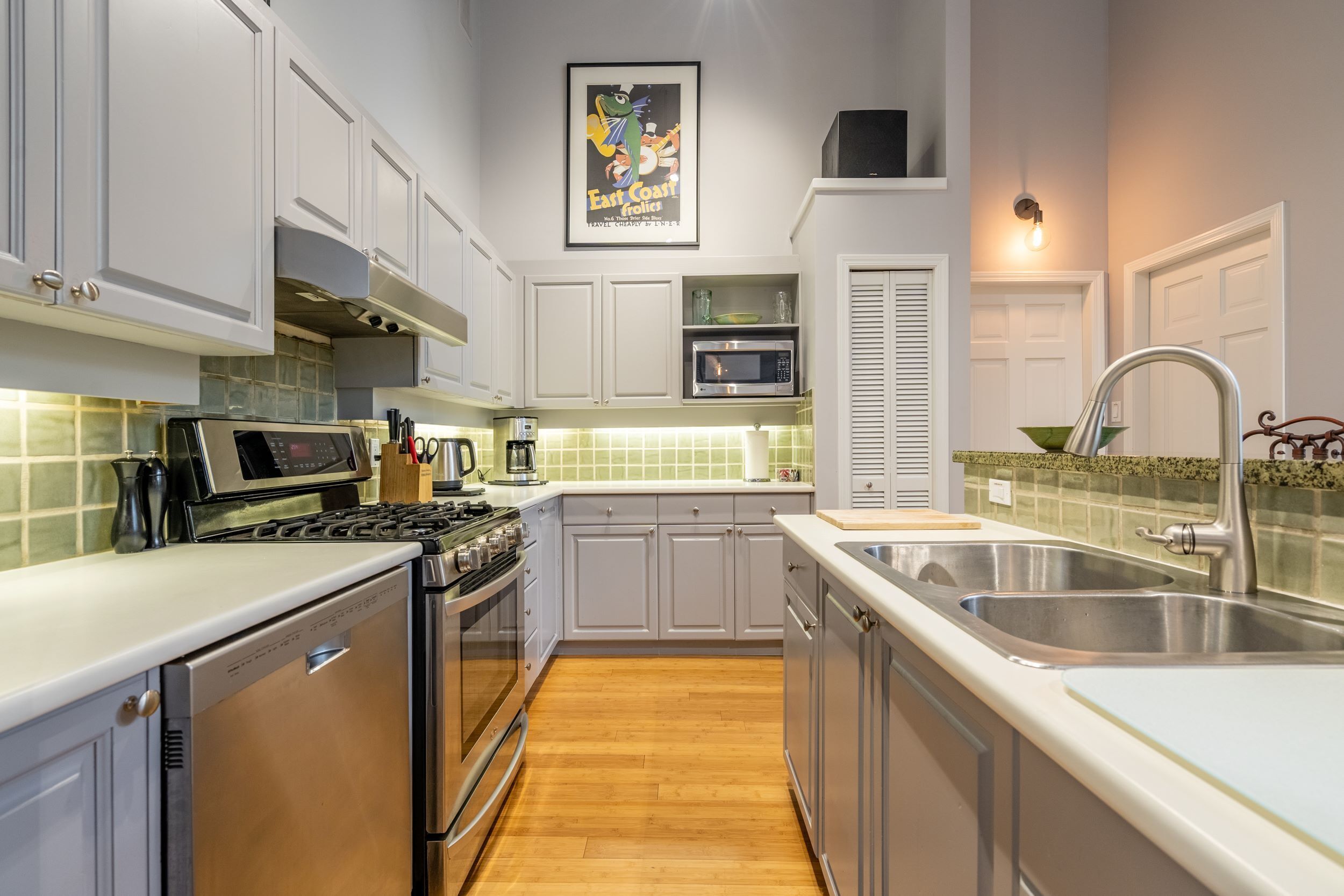 A modern kitchen with white cabinets, stainless steel appliances, and a tiled backsplash.