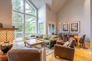 Relax in this spacious living area with a high ceiling and large windows offering a view of the outdoors. Enjoy comfortable seating and dining for six.