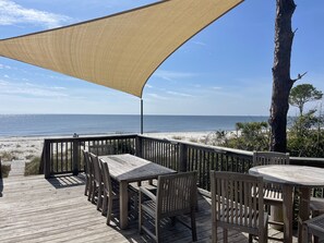A wooden deck with outdoor seating and a view of the beach. - BEACH FRONT to BAY with boatdock, swimming pool, pickleball courts and  kayaks. (Panacea)