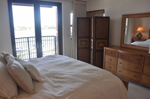 Een hotelkamer met een bed, een kaptafel, een spiegel en een balkon met uitzicht.