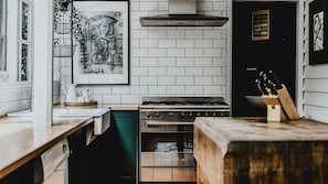 Una cocina con azulejos blancos tipo metro, una estufa de acero inoxidable y una encimera de madera.