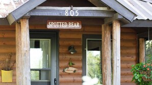 A wooden cabin with a sign reading "805 SPOTTED BEAR" above the door.