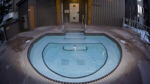 Ein Innenpool mit einer gefliesten Kante, eine Treppe zu einer Tür und ein Metallgeländer.