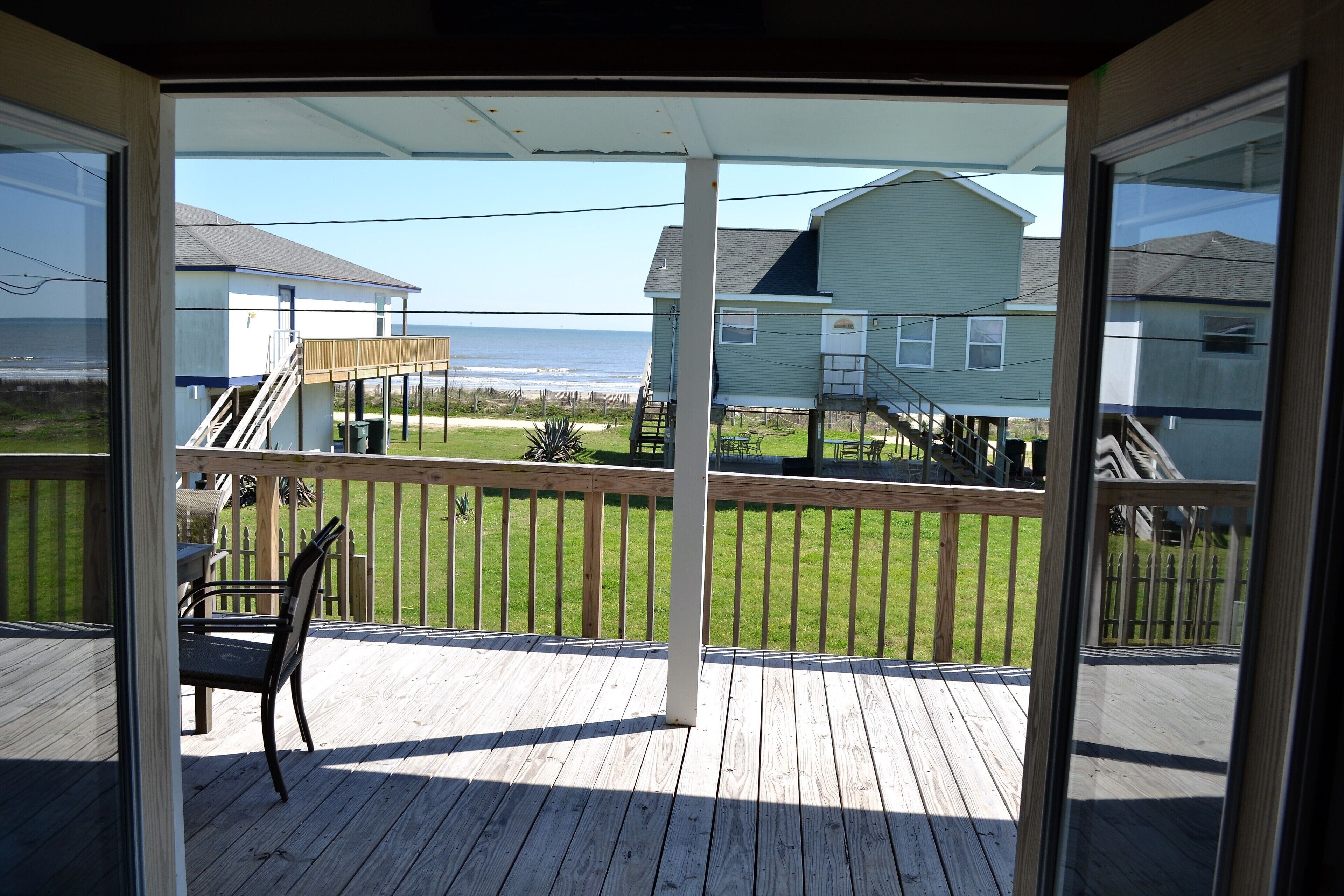 A wooden deck with a chair, a staircase, and a view of the ocean and houses.