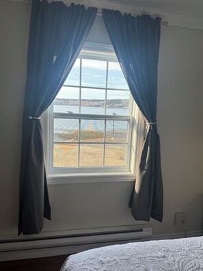 Ein Zimmer mit Fenster, Vorhängen, einem Bett und einer Steckdose.