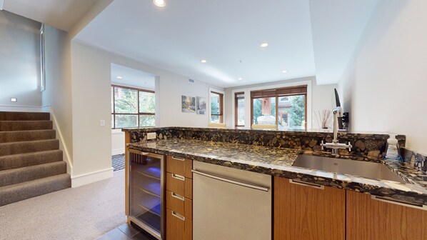 A modern kitchen with a granite countertop, wooden cabinets, and a stainless steel dishwasher. - Fitzsimmons #33 Luxury 4 Bedroom, Private Hot Tub, BBQ (Whistler)