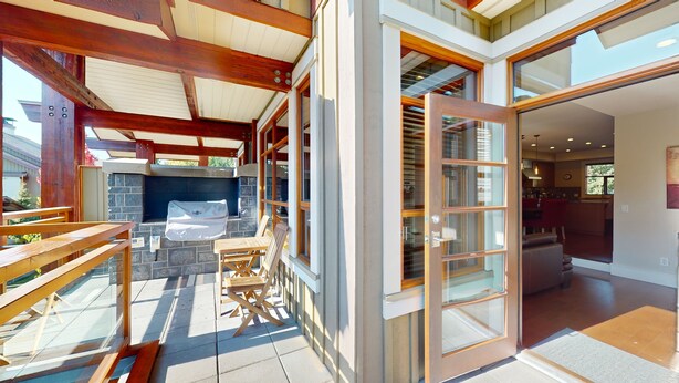 Un espace extérieur abrité, doté d’une cheminée en pierre, de bancs en bois et d’une chaise pliante.