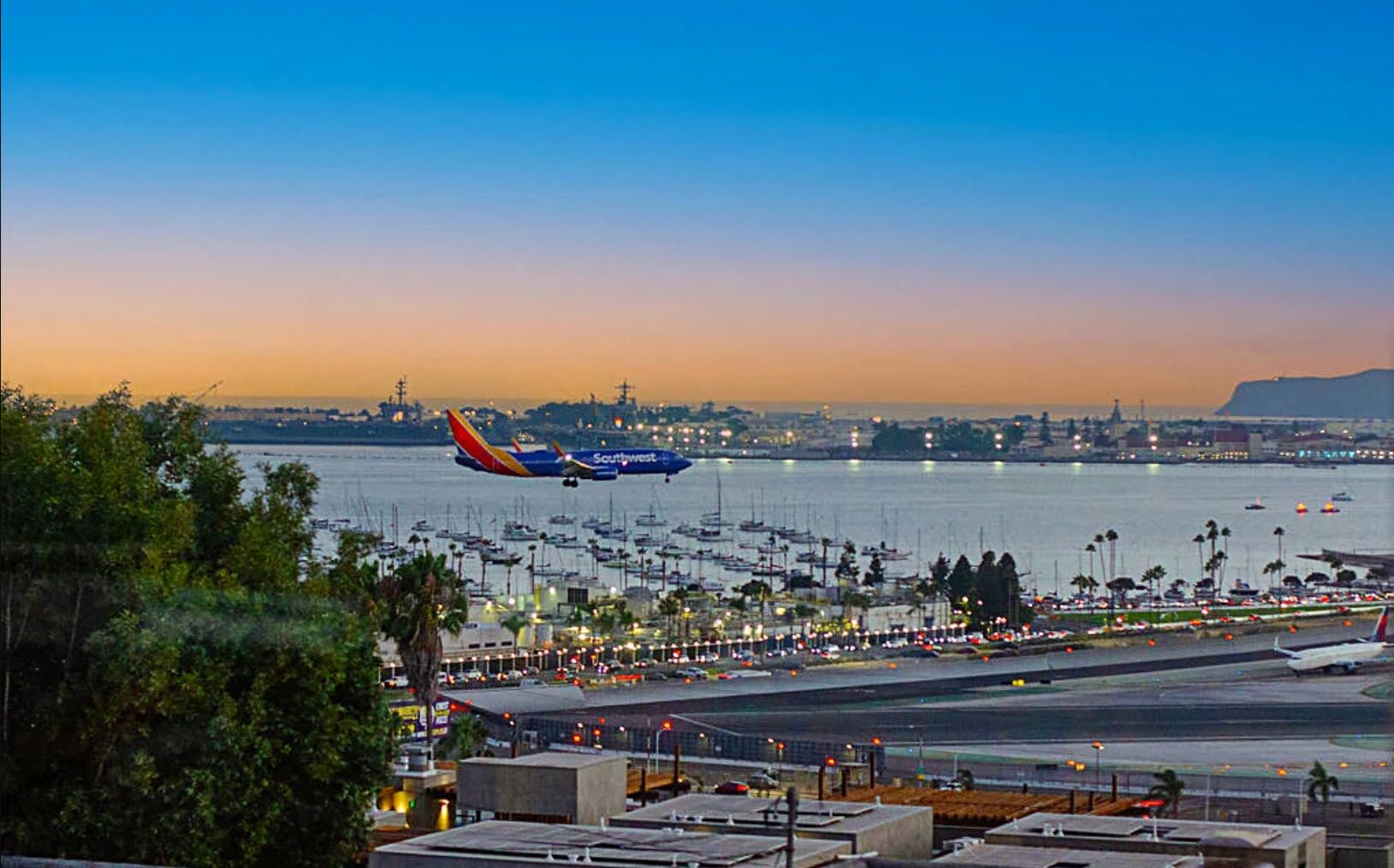 An airport with a Southwest Airlines plane on the runway, surrounded by parked cars and boats.