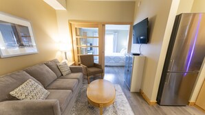 A modern living room with a sofa, armchair, coffee table, and a TV mounted on the wall.
