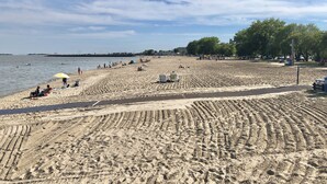 A sandy beach with people, a playground, and trees.