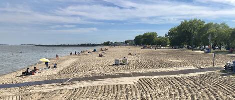 Ein Sandstrand mit Menschen, einer Spielplatz und Bäumen.