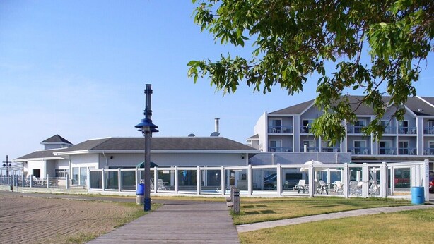A wooden boardwalk leading to a building with multiple balconies and covered seating areas.