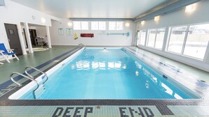 A swimming pool with a 'DEEP END' sign, clear water, and a tiled floor.