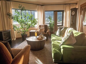 A cozy living room with a fireplace, green sofa, armchair, and two potted plants. - Walk everywhere from Railtown Suite! + spacious, beautiful, & comfortable. (Nelson)