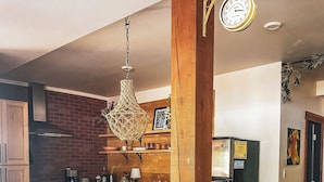 A kitchen with a central island, wooden cabinets, a hanging light fixture, and a refrigerator. - Walk everywhere from Railtown Suite! + spacious, beautiful, & comfortable. (Nelson)