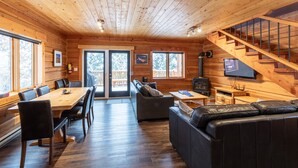 Ein Holzhütten-Interieur mit Essbereich, Sofa und Treppe.