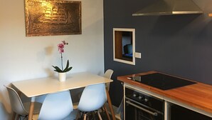Una cocina moderna con una mesa blanca, dos sillas, una lámpara colgante, una estufa y un microondas.