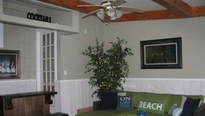 A cozy living area with a green couch, a coffee table, and a bar area labeled 'COCKTAILS'.
