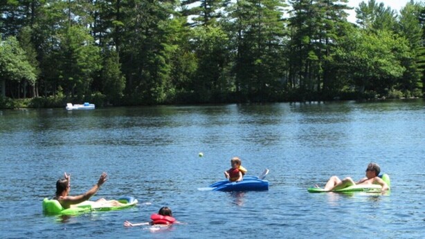 A group of people floating on a lake surrounded by trees.
