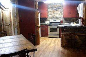 A kitchen with wooden cabinets, a stove, and a dining area with a wooden table and chairs.