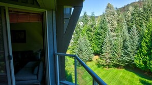 A balcony with a view of a well-maintained lawn and dense forest. - Aspens #549 Prime Ski-in Ski-out Location! Top Floor Unit, Pool, Hot tubs, BBQ (Whistler)