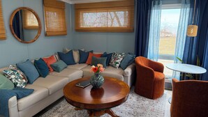 A living room with a beige sofa, a round wooden coffee table, and a small round table with a chair.