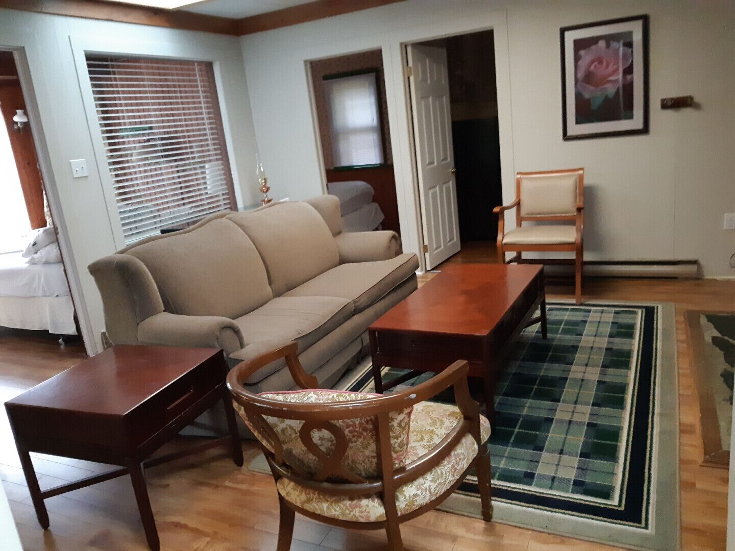 Una sala de estar con un sofá beige, una mesa de centro de madera y un sillón estampado.