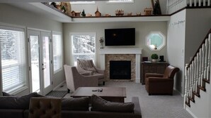 A living room with a fireplace, a television, and a staircase.