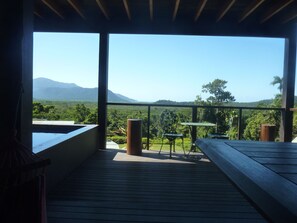 A wooden deck with a table and chairs, overlooking a lush landscape with mountains in the distance. - Daintree Holiday Homes - La Vista - Ocean Views with Private Pool & Jet Spa (Daintree)