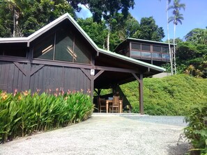 A rustic building with a covered porch and a balcony overlooking a lush garden. - Daintree Holiday Homes - La Vista - Ocean Views with Private Pool & Jet Spa (Daintree)