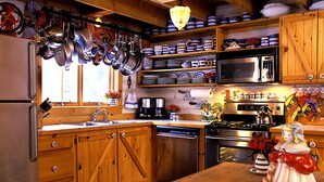 Cozinha com armários de madeira, eletrodomésticos de aço inoxidável e diversos pratos e utensílios.