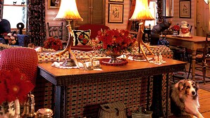 Um quarto acolhedor com uma mesa de madeira, duas luminárias, um candelabro e um cão deitado no chão.