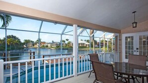 A covered outdoor area with a pool, white railings, and a table with chairs. - 3/2 Home steps away from Tiger Tail access (Marco Island)