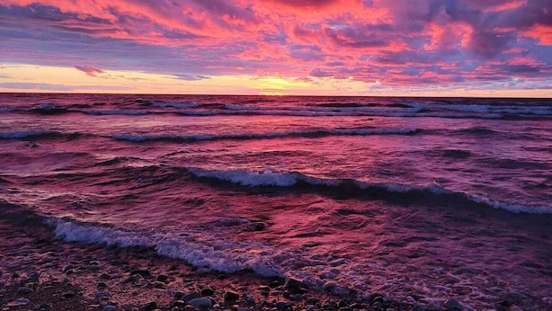 Een strand met golven en een zonsondergang.